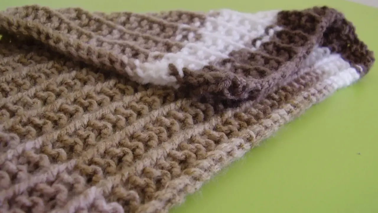 Bufanda tejida con patrones puntos reversibles a dos agujas, en tonos marrones y blanco.