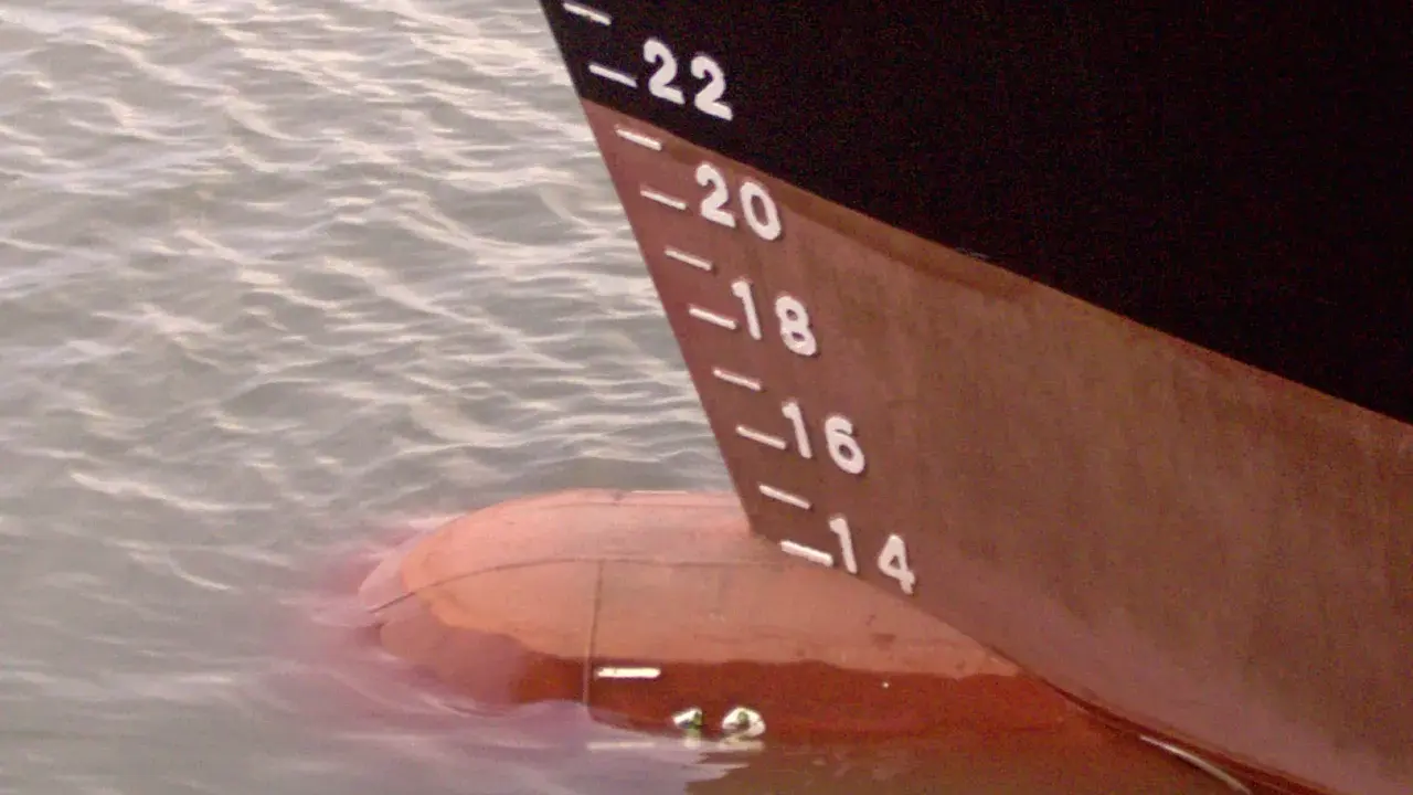 La coque d'un navire, marquée de -22 à -14, flotte sur l'eau. Le déplacement léger du bateau est visible.