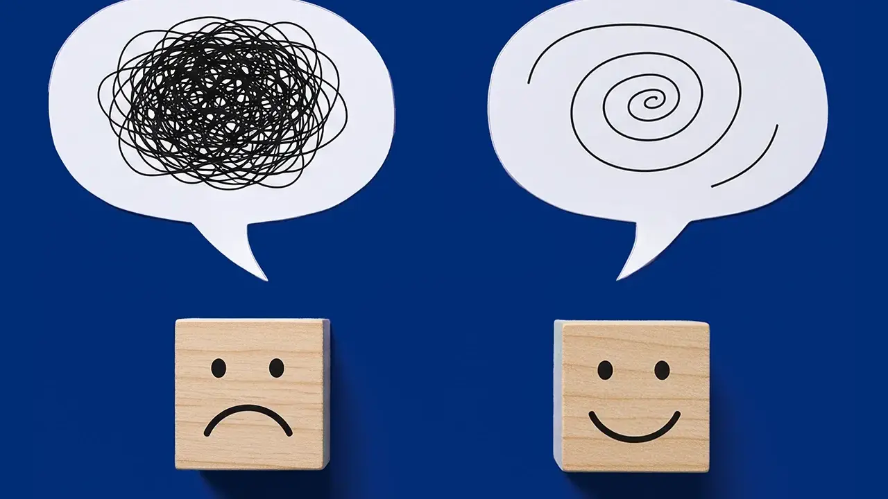 Dwa dymki myśli: jeden z chaotyczną linią, drugi ze spiralą. Pod nimi kostki z minami: smutną i uśmiechniętą. Przykłady zaburzeń emocjonalnych i ich przezwyciężania.