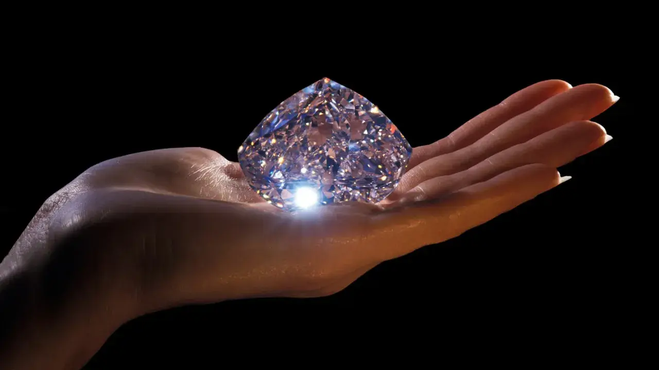 Mano che regge un enorme diamante scintillante, simbolo di eternità e amore. Il diamante significato è immenso.