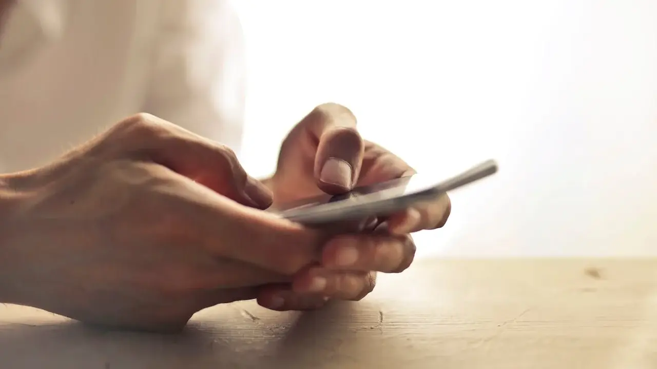 Dłonie trzymające telefon, jakby zastanawiając się, czy na odwyku można mieć telefon.