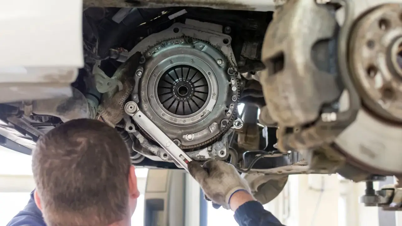 Mechanik dokonuje wymiany sprzęgła w Nissan Qashqai 1.6 benzyna. Widoczny jest mechanizm sprzęgła i narzędzia.