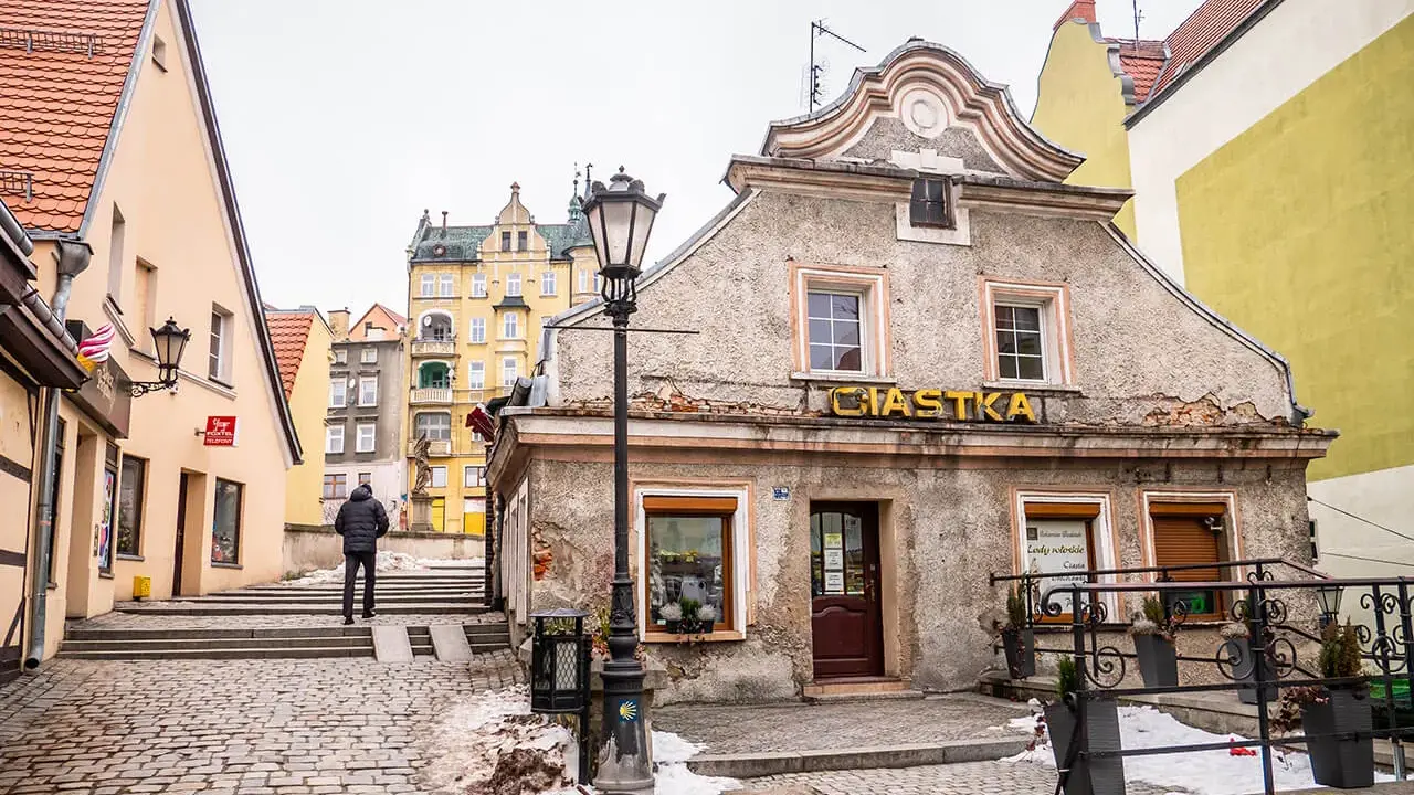 Kłodzko rynek. Kamienne uliczki i kolorowe kamienice tworzą urokliwy klimat. Na pierwszym planie budynek z napisem "Ciastka".