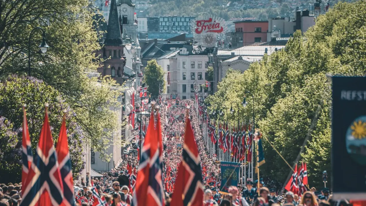 Tłum ludzi na ulicy w Oslo, z norweskimi flagami. Czy Norwegia jest w NATO? Tak, jest członkiem od 1949 roku.