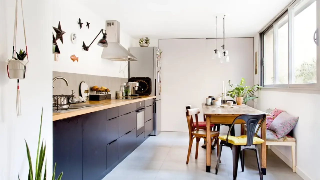 Cuisine sans placard haut, avec des meubles bas sombres, un plan de travail en bois et une table à manger.