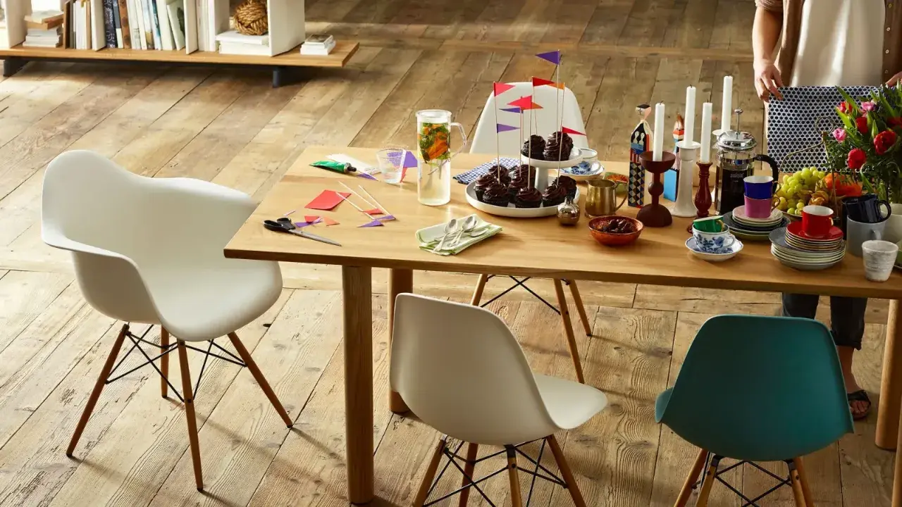 Tavolo in legno con sedie Eames House, cupcake, candele e fiori. Un'atmosfera accogliente per una festa.