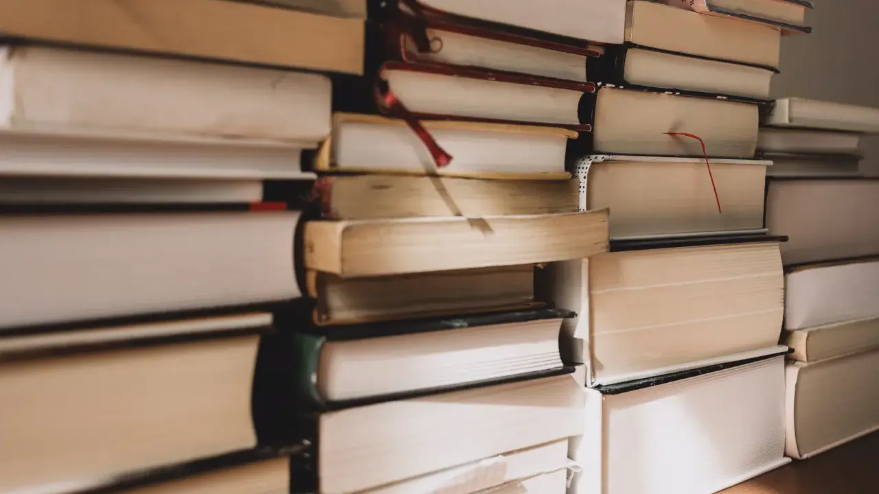 Pile di libri, alcuni con segnalibri rossi, pronti per essere letti. Ecco i miei ultimi libri consigliati.
