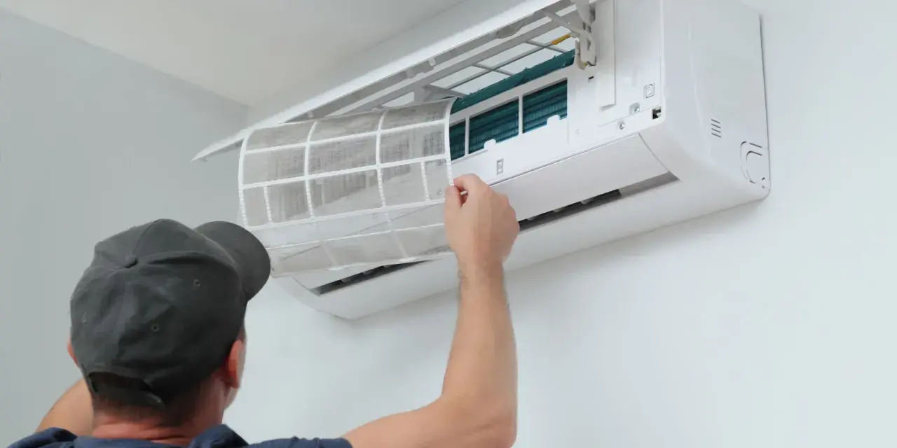 Un technicien retire un filtre sale d'une climatisation. Un entretien régulier est essentiel pour le prix et l'efficacité de votre climatisation.