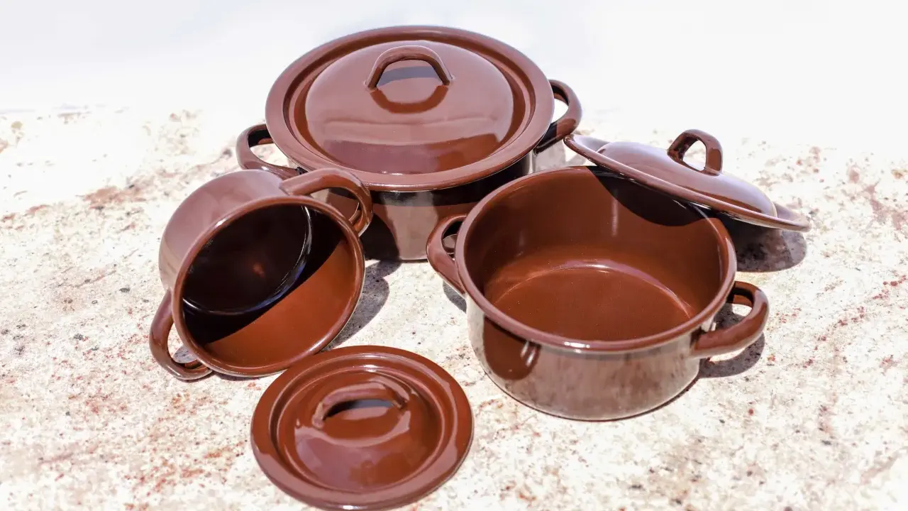 Conjunto de cazuelas de barro esmaltada en marrón. Listas para curar y preparar deliciosos guisos.