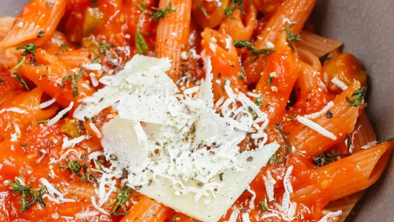 Szybki obiad z makaronem penne w sosie pomidorowym, posypany parmezanem i ziołami. Idealny na szybki posiłek.