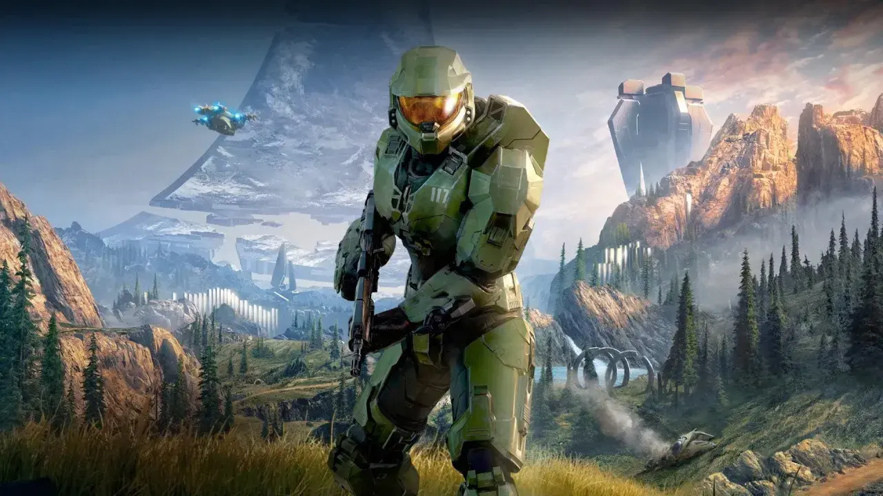 Master Chief w zbroi z Halo Infinite stoi na tle górskiego krajobrazu z pierścieniem Halo i pojazdem UNSC.
