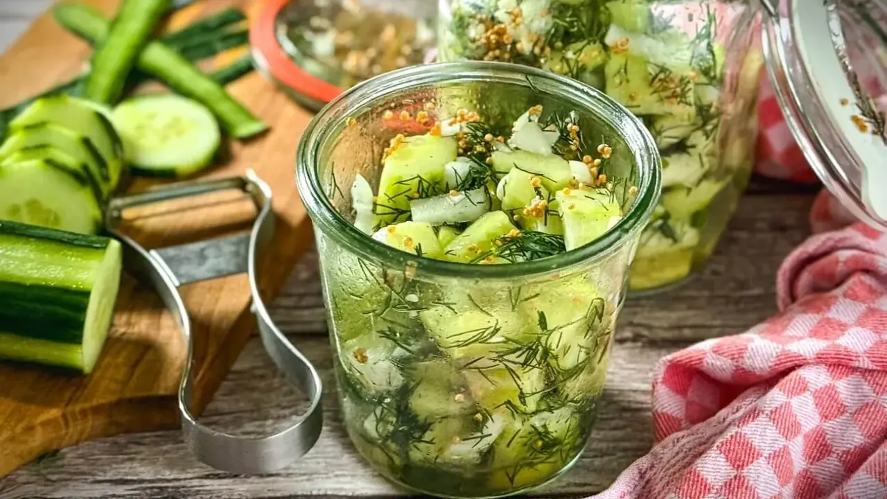 Schnellgurken rezept ohne kochen: Frische Gurkenscheiben mit Dill und Senfkörnern in Gläsern, bereit zum Einlegen.
