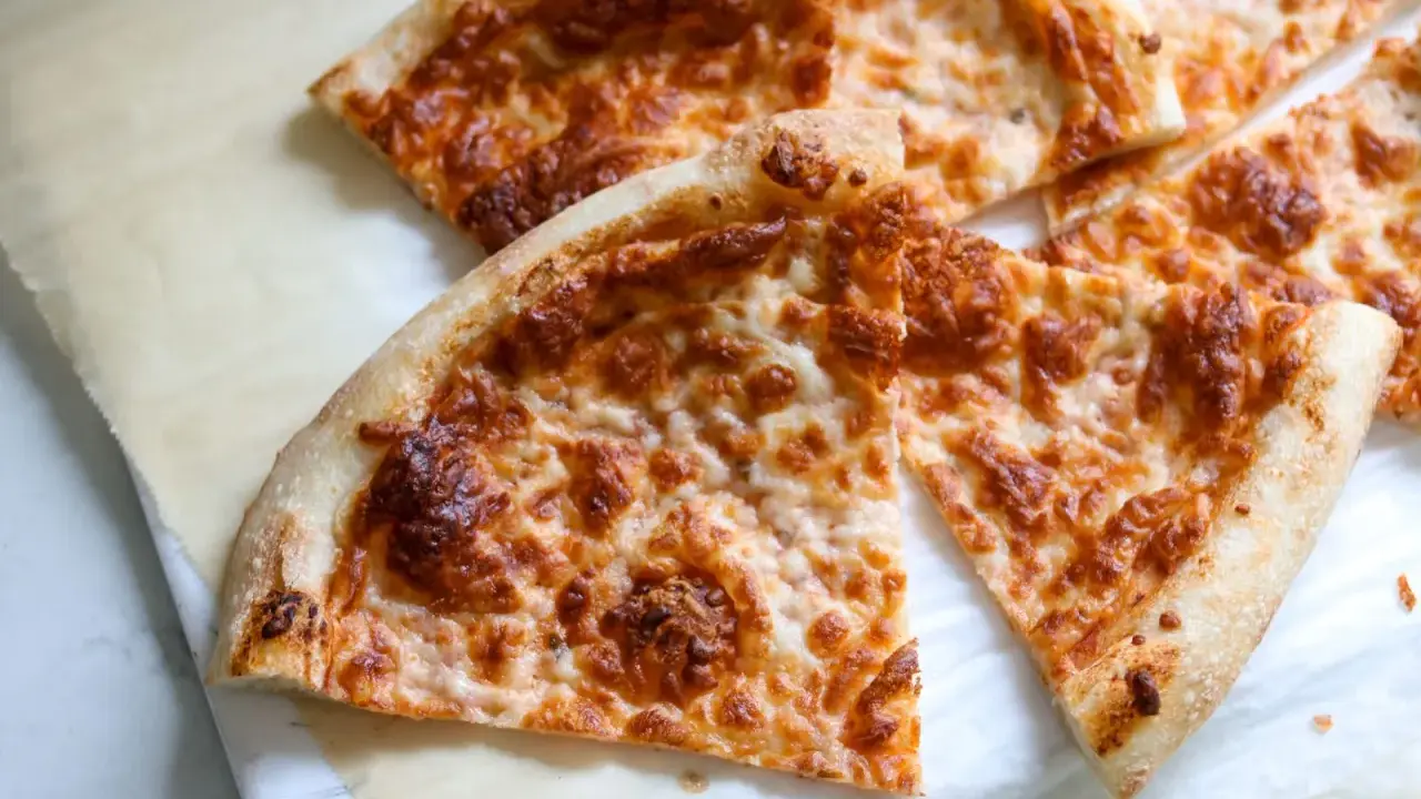 Tranches de pizza au fromage doré, préparées avec un levain rafraichi, sur du papier sulfurisé.
