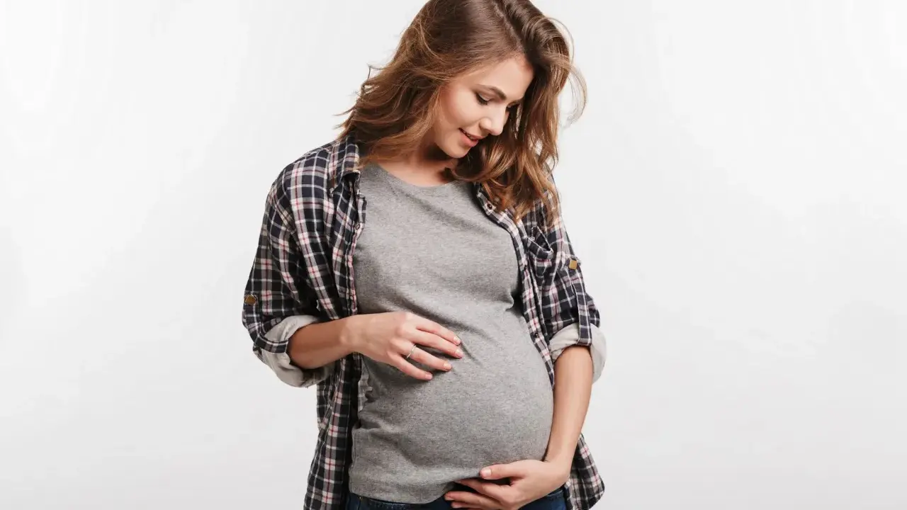 Kobieta w ciąży delikatnie dotyka brzucha. Częste oddawanie moczu w ciąży to normalny objaw.
