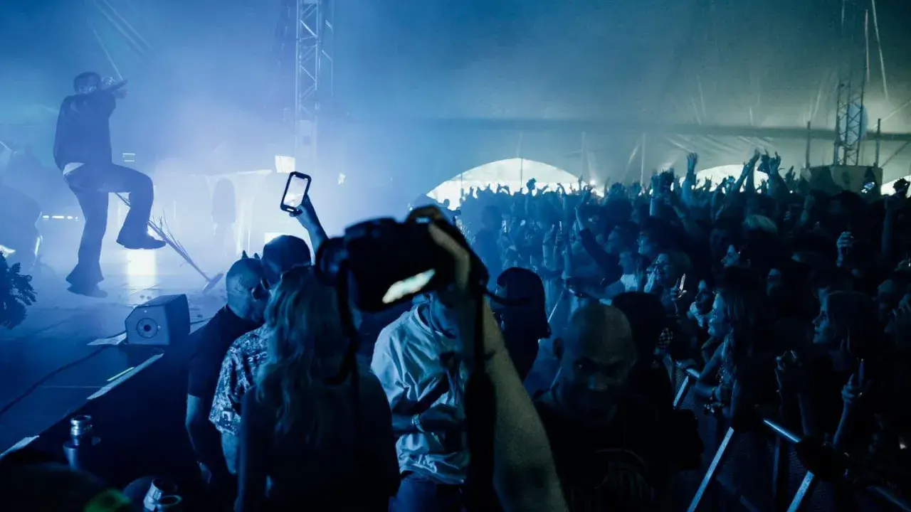 Publik jublar på en konsert i Göteborg. En artist uppträder på scenen i blått ljus och rök. Många i publiken filmar med sina mobiler.