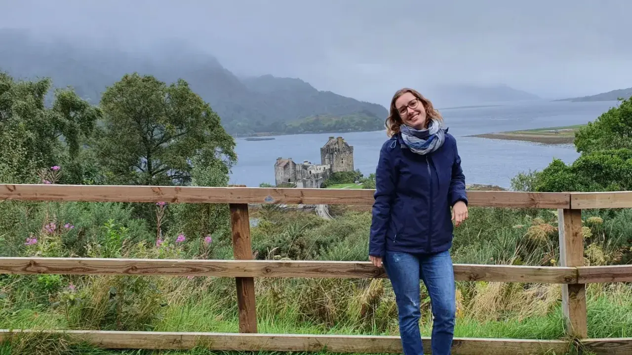 Frau vor schottischer Burg bei typischem Septemberwetter. Die Landschaft ist grün, das Wetter schottland september ist wechselhaft, aber die Stimmung ist gut.