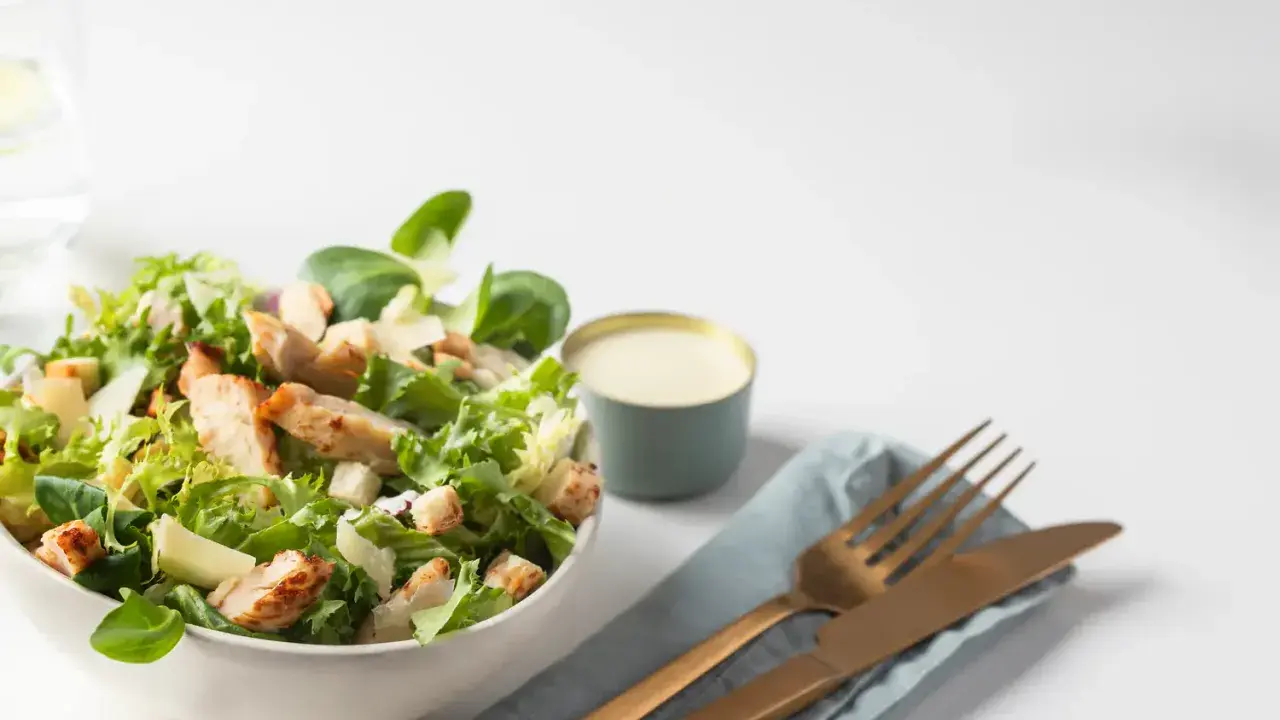 Salade César fraîche avec poulet grillé, croûtons et copeaux de parmesan, accompagnée de sa sauce crémeuse.