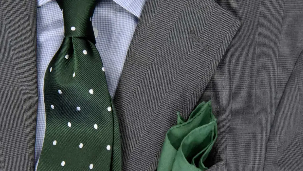 Zielony krawat w kropki do niebieskiej koszuli i szarej marynarki. Elegancka stylizacja.