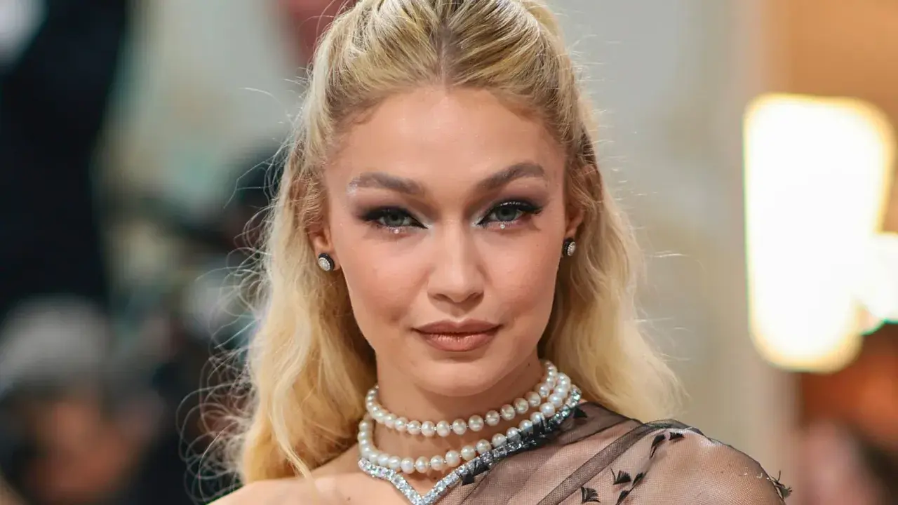 Gigi Hadid luce un maquillaje con perlas, con pequeños adornos brillantes en los ojos y un collar de perlas.
