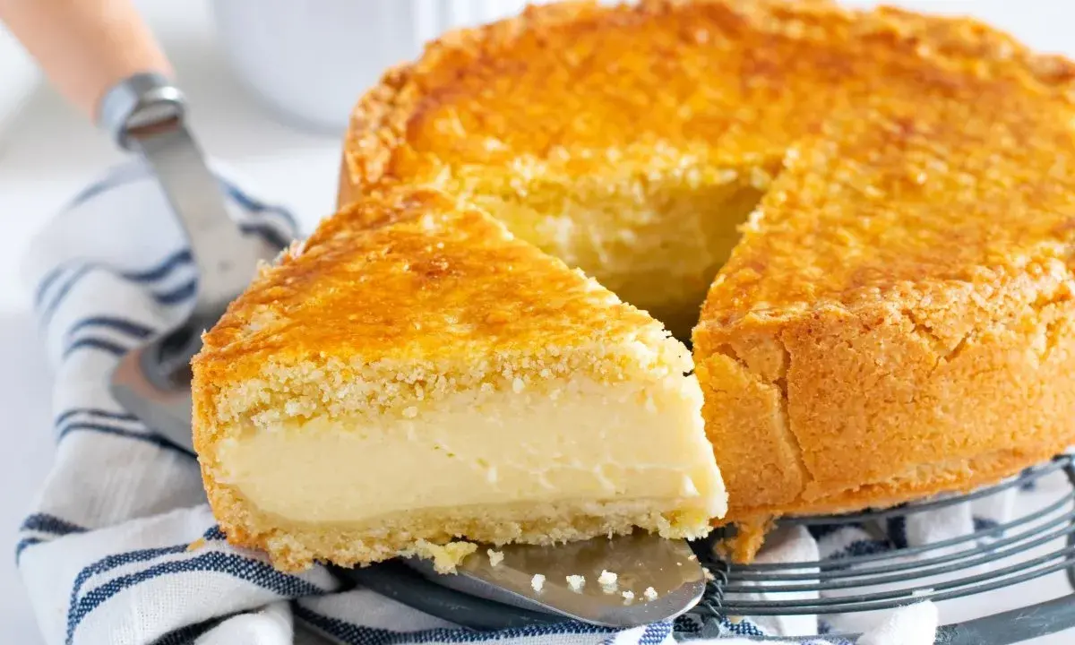 Un delicioso pastel vasco con una porción cortada, mostrando su relleno cremoso y su dorada corteza.