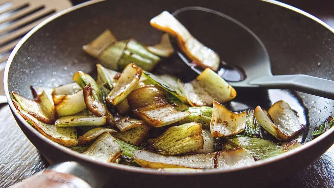 Gebratener Mangold und Pak Choi in einer Pfanne, leicht karamellisiert und mit einem Löffel serviert.
