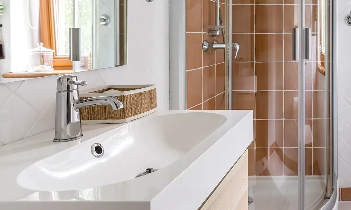 Bagno moderno con lavabo bianco, rubinetteria cromata e doccia con piastrelle color terra. Ideale per misure minime mini bagni piccoli progetti.