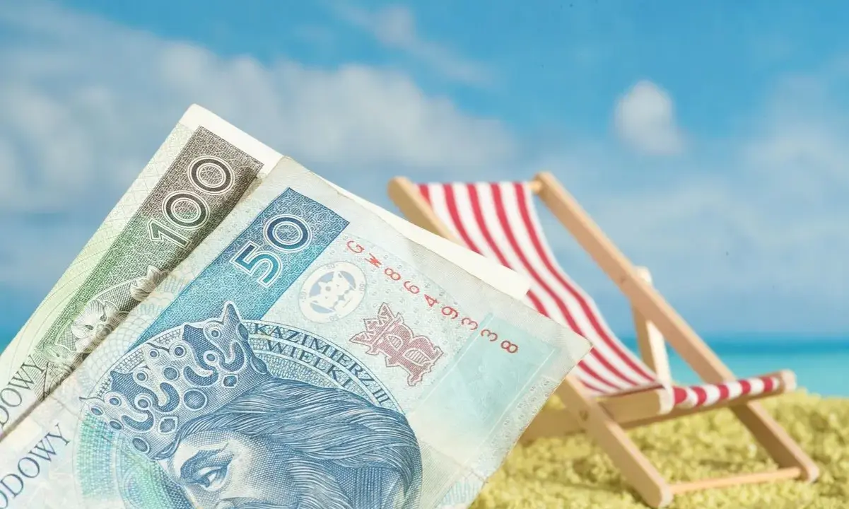 Pieniądze na plaży, leżak i błękitne niebo. Czy to symboliczne przedstawienie opłaty klimatycznej za wakacyjny wypoczynek?