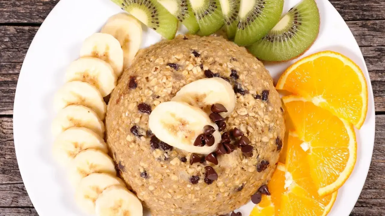 Un délicieux bowl cake flocon d'avoine, garni de rondelles de banane, de tranches de kiwi et d'orange, parsemé de pépites de chocolat.