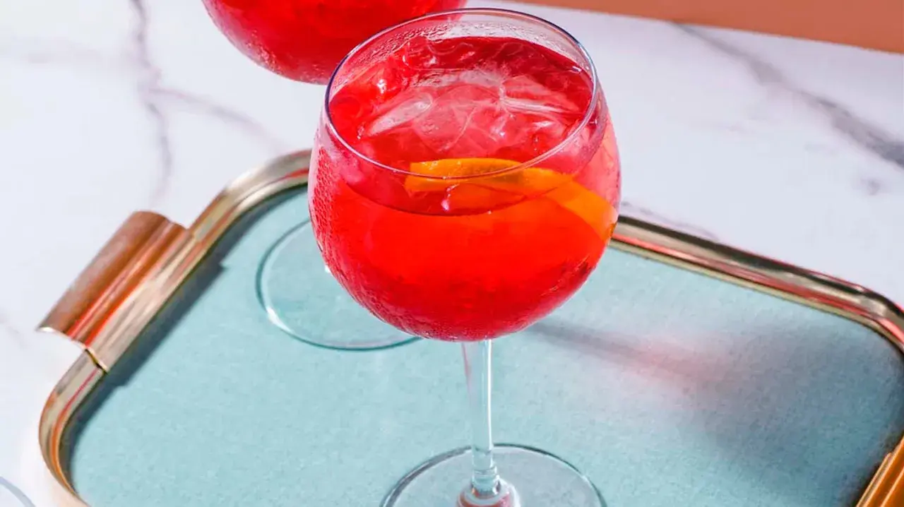 Ein erfrischender Campari Spritz mit Eis und Orangenscheibe auf einem Tablett.