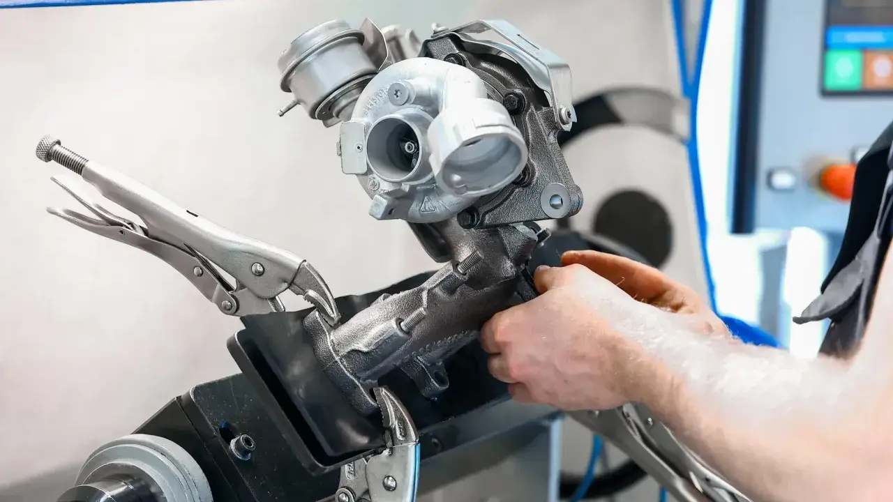 Mechanik naprawia turbosprężarkę. Uszkodzony elektrozawór turbiny objawy mogą być różne, ale ten element jest kluczowy.