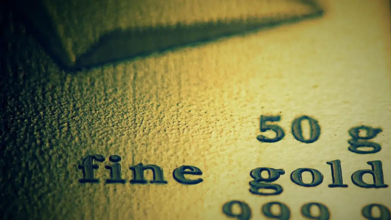 Zbliżenie na tekst "fine gold 50 g 999,9" wybity na powierzchni złota.