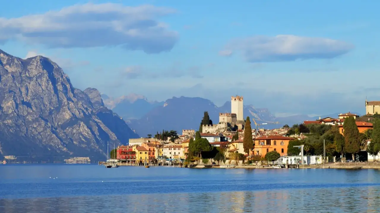 Borgo sul lago di Garda con castello e montagne sullo sfondo. Un luogo incantevole da esplorare, scopri cosa vedere!