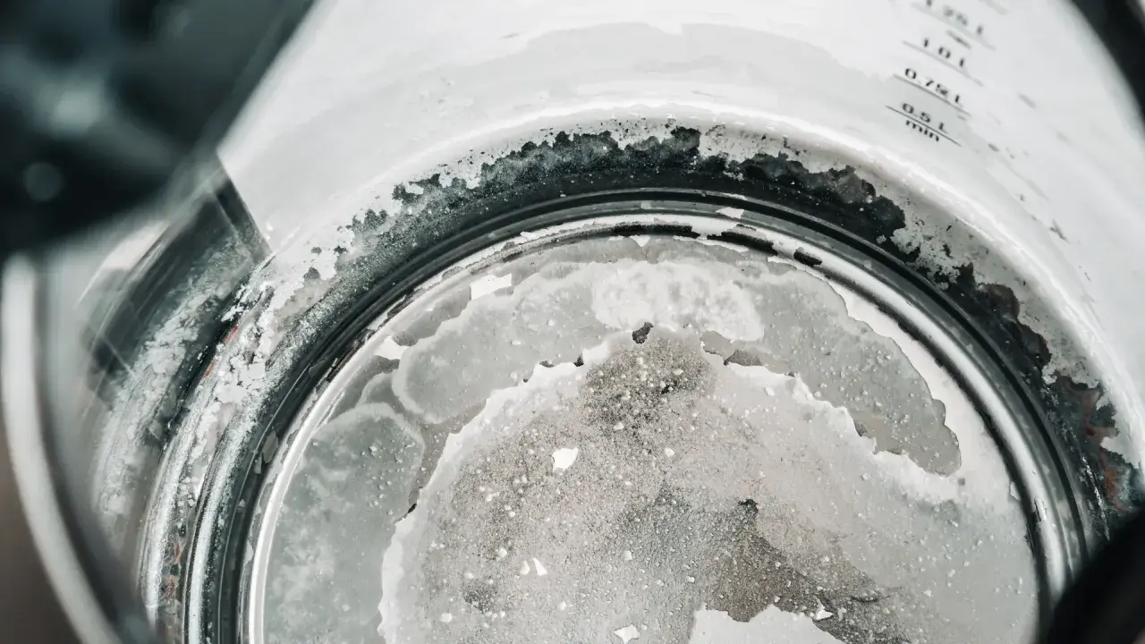 Dépôt calcaire dans une bouilloire, témoignant de la dureté de l'eau par ville. Les résidus blancs et gris indiquent une forte concentration de minéraux.
