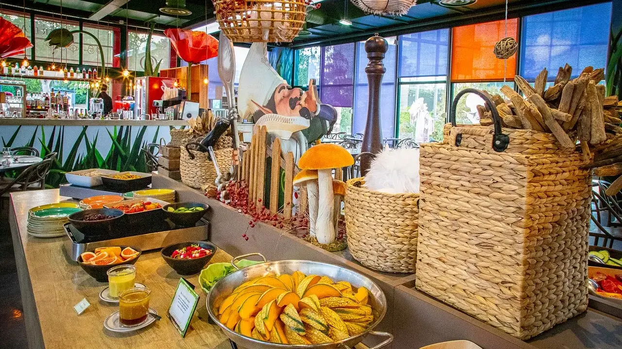 Buffet coloré avec des plats de courges, salades et fruits. Décoration ludique avec des champignons et un personnage de conte de fées, dans l'ambiance du resto Futuroscope.