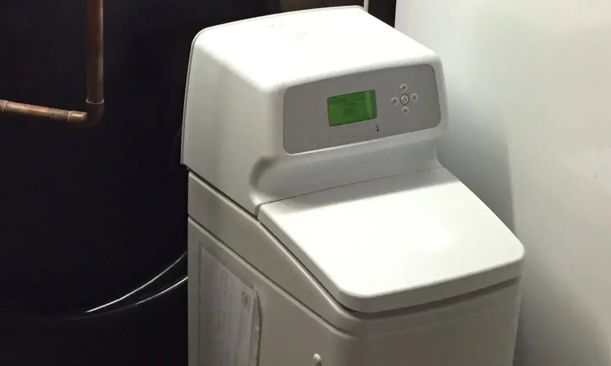 Adoucisseur d'eau blanc avec écran vert, un avantage pour une eau plus douce et une maison protégée.