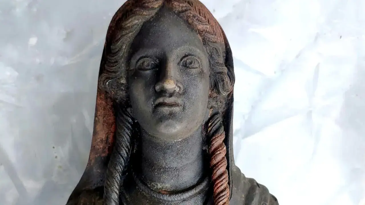 Statua antica ritrovata nel santuario di San Casciano dei Bagni, con capelli intrecciati e volto enigmatico.
