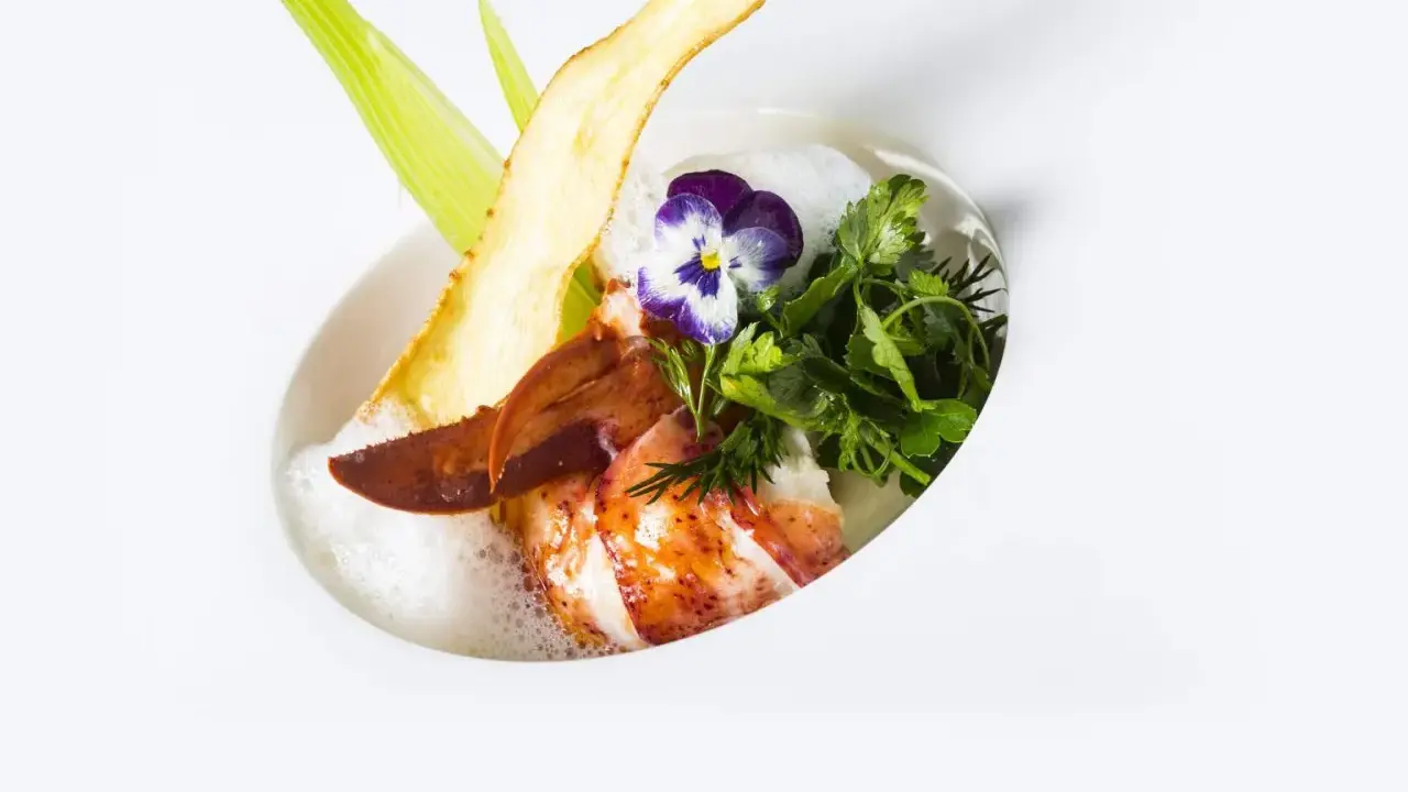 Homard poêlé, écume légère, chips de légume et fleur, une spécialité jurassienne raffinée.