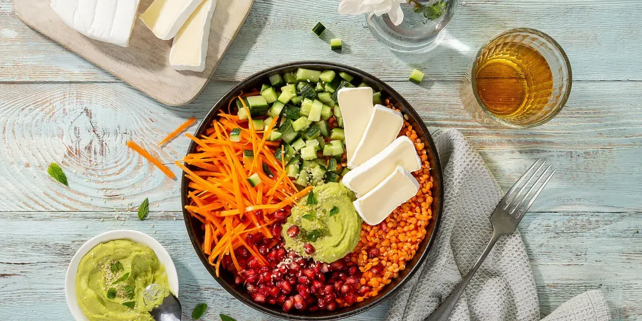 Bunter rote Linsen Salat mit Gurke, Karottenstreifen, Granatapfelkernen, Avocado-Dip und Brie-Käse.