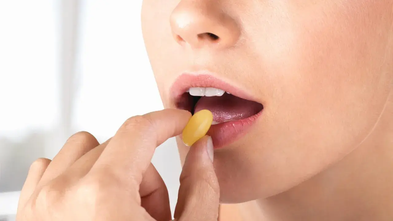Donna inserisce una capsula gialla in bocca. Per l'assunzione di Ciproxin, stomaco pieno o vuoto, consultare il medico.