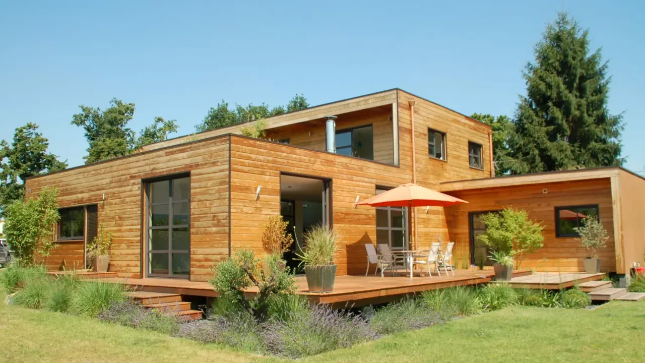 Maison moderne en bois avec terrasse et jardin. La construction maison ossature bois met en valeur le matériau naturel.