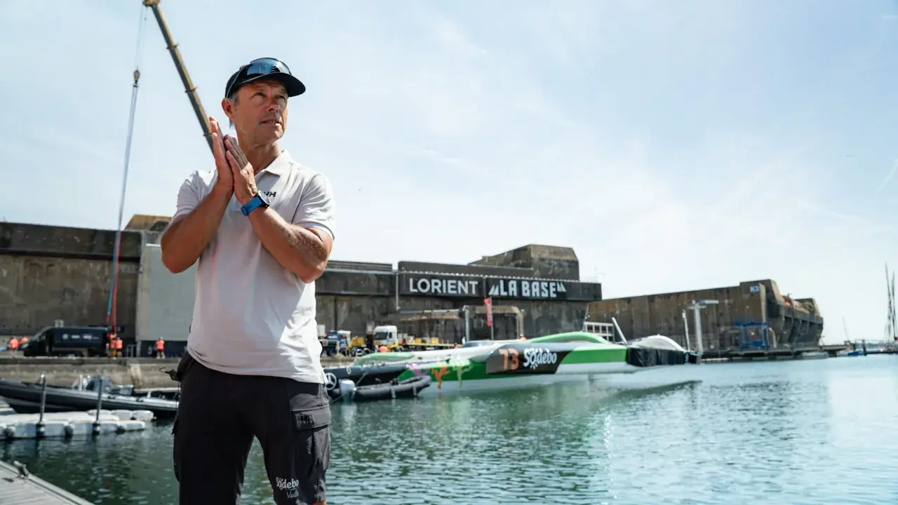Un homme applaudit devant le trimaran Sodebo Ultim 4, prêt à naviguer.