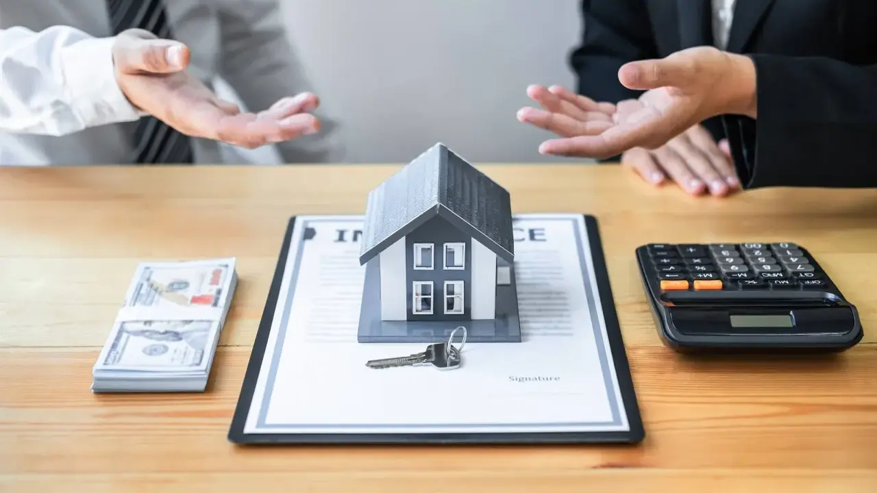 Negociación de honorarios inmobiliaria: casa modelo, llave, dinero y calculadora sobre un contrato.
