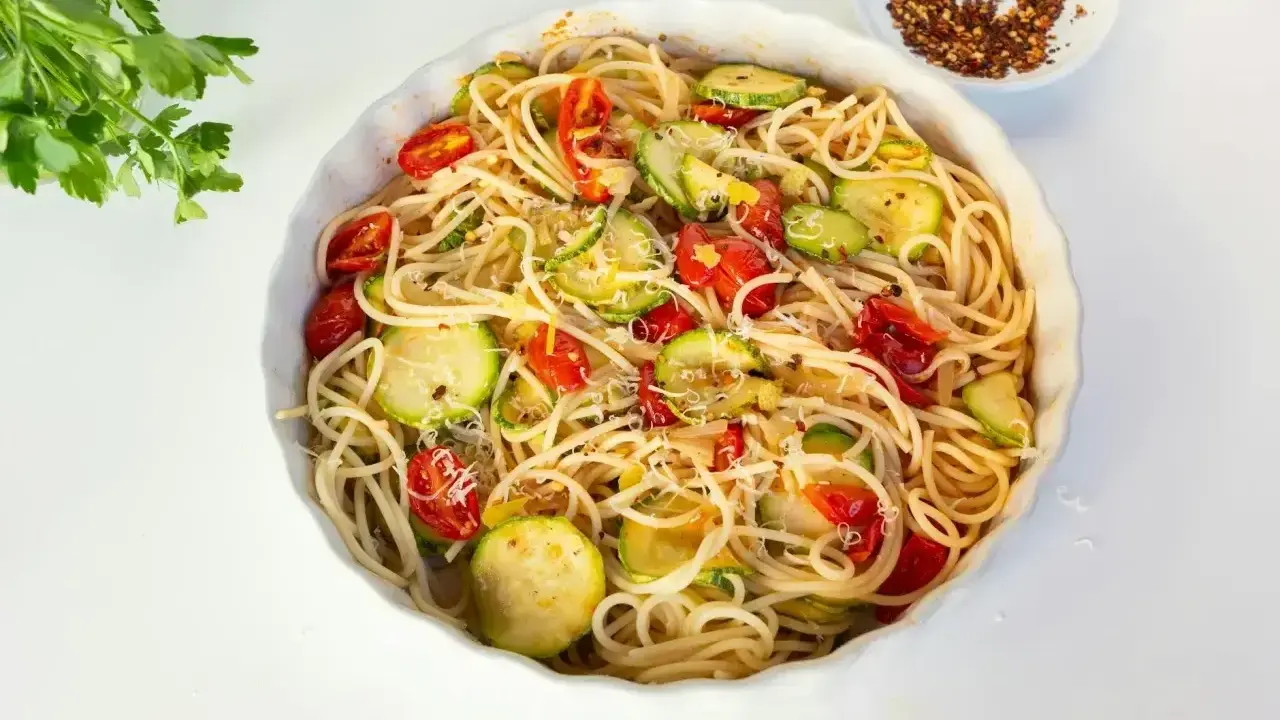 Pyszny makaron z cukinii, pomidorkami i parmezanem, gotowy do podania.