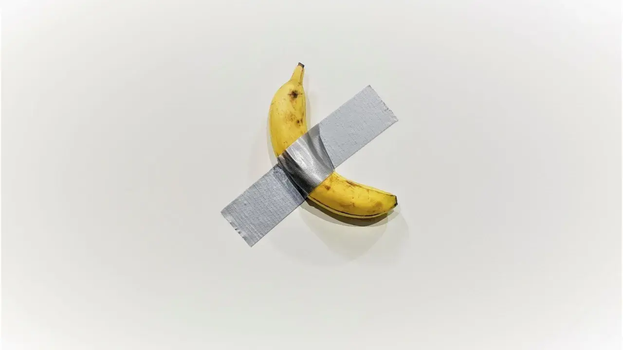 A ripe banana, a symbol of Maurizio Cattelan's art, is taped to a white wall.