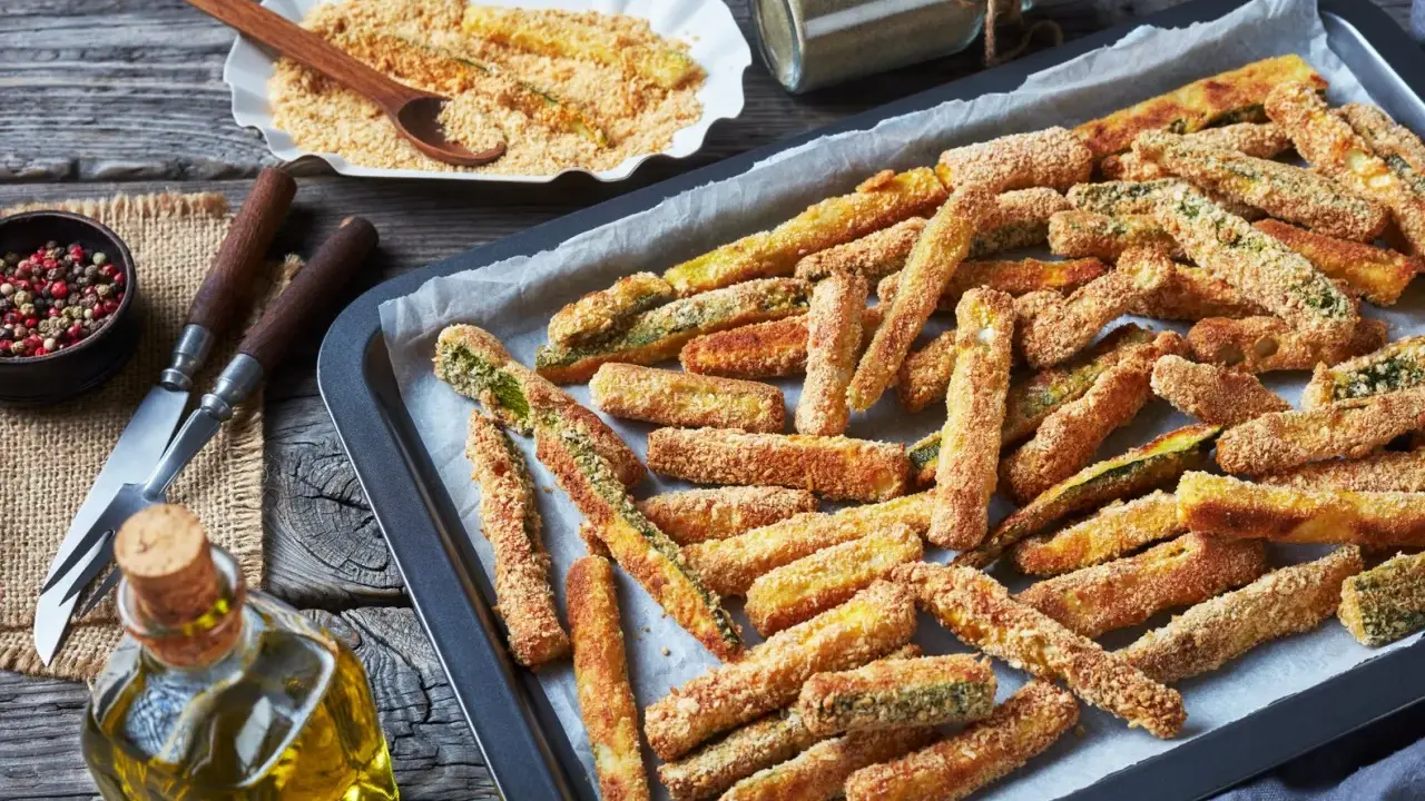 Fettine dorate di chips di zucchine pronte per essere gustate, su una teglia da forno.