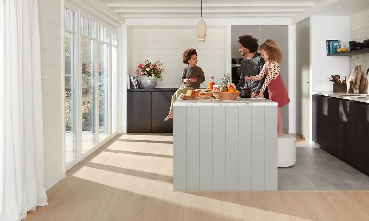 Une famille prépare un repas dans une cuisine moderne. La **délimitation sol cuisine salon** est subtile, avec un parquet clair contrastant avec le carrelage du salon.