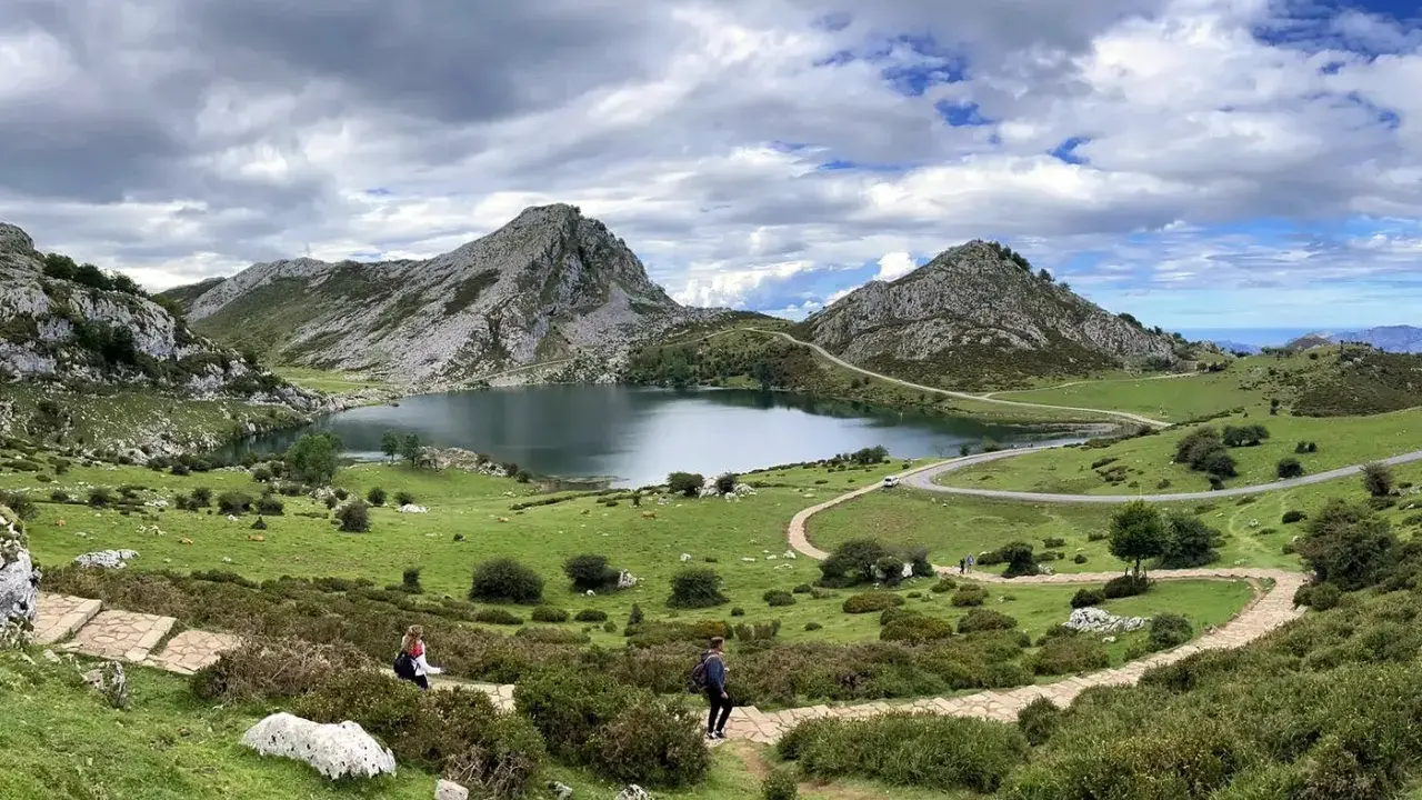 Zwei Wanderer genießen die Herbstlandschaft mit einem See und Bergen. Ein perfekter Tag zum Wandern im November.