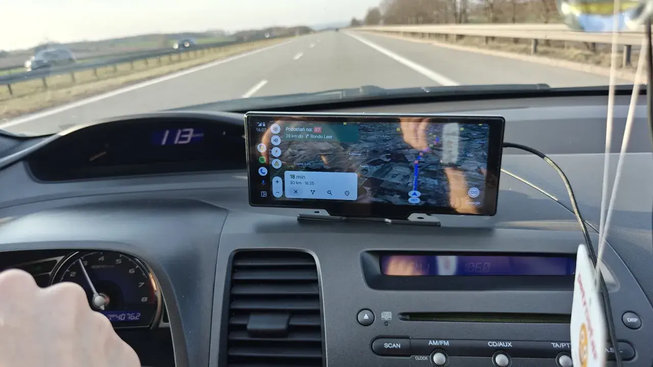 Na ekranie w samochodzie widać nawigację z funkcją co to jest carplay. Pokazuje trasę, odległość i czas dojazdu.