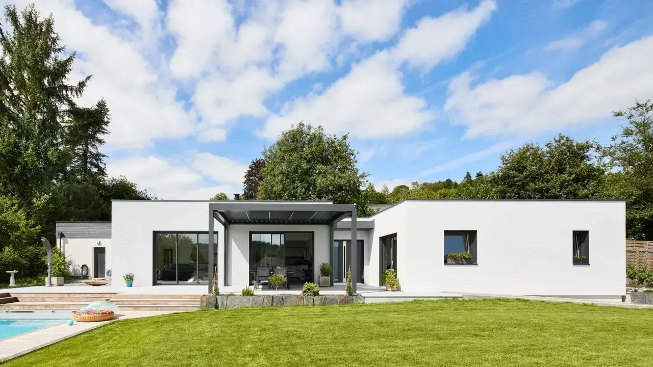 Une maison modulable moderne avec piscine et jardin luxuriant, sous un ciel bleu éclatant.