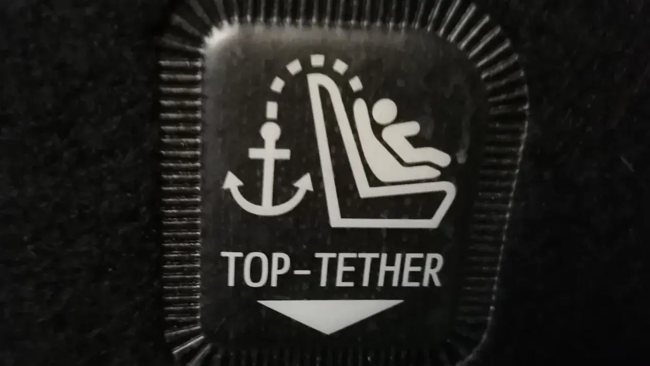 Symbol mocowania fotelika ISOFIX z kotwicą i dzieckiem. To jest oznaczenie TOP TETHER.